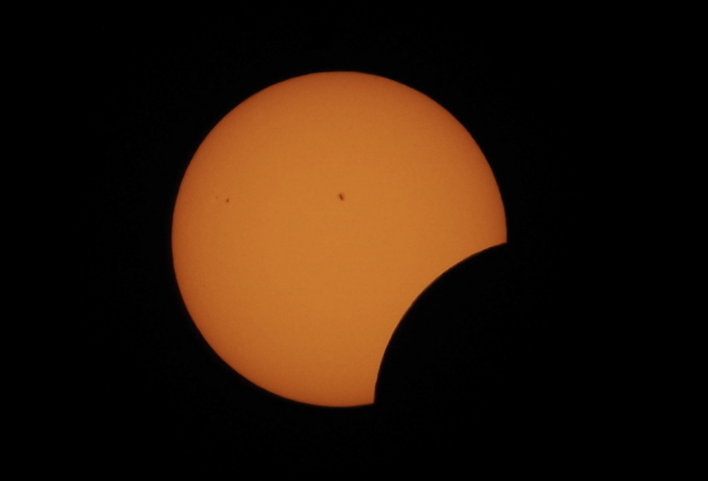 A partial solar eclipse, with the moon partially covering the sun.